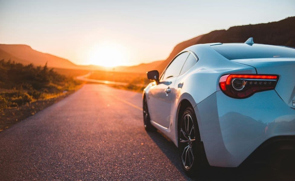 White sports car on open road at sunset on a summer road trip